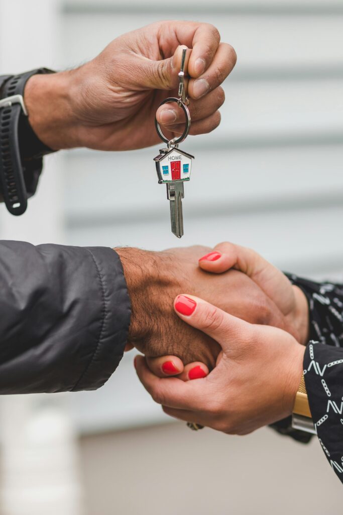pexels photo 8293654 8293654 Close-up of a handshake with a house key, symbolizing real estate transactions.